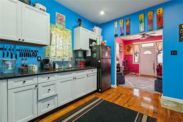 kitchen with white cabinetry, sink, dark hardwood / wood-style floors, and black fridge