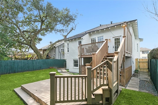 back of property featuring a wooden deck and a lawn