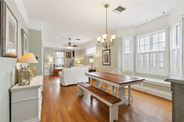 dining area with hardwood / wood-style flooring and ceiling fan with notable chandelier