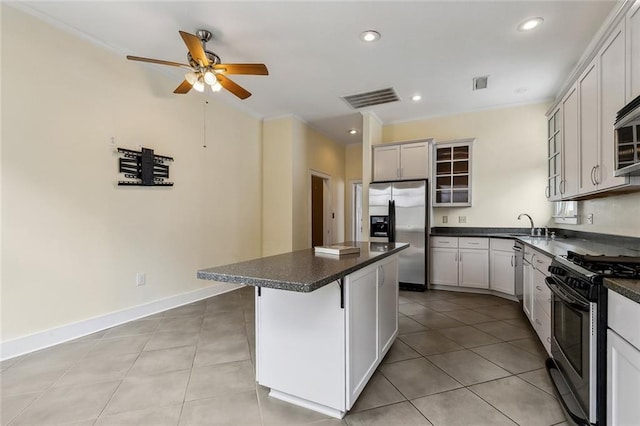 kitchen featuring ceiling fan, stainless steel appliances, a kitchen breakfast bar, a center island, and light tile patterned flooring