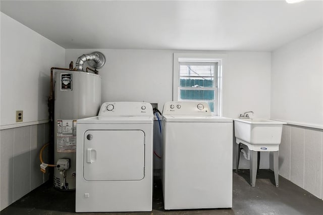 laundry area with water heater, washer and dryer, and sink