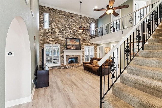 living room featuring a high ceiling, ceiling fan, hardwood / wood-style floors, and a fireplace