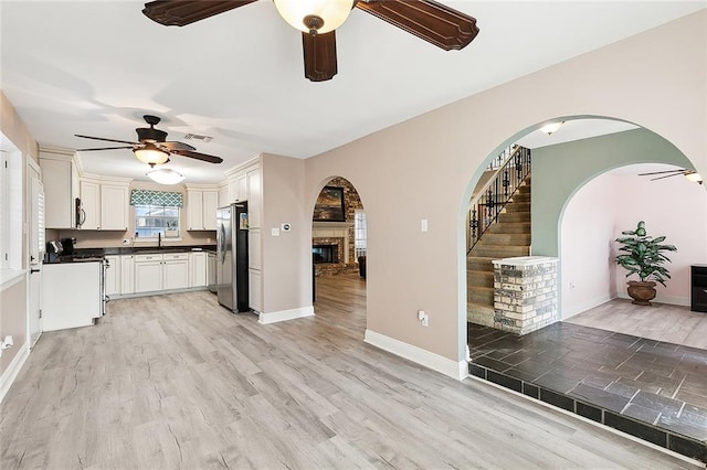 kitchen featuring stainless steel appliances, white cabinetry, ceiling fan, and light hardwood / wood-style flooring