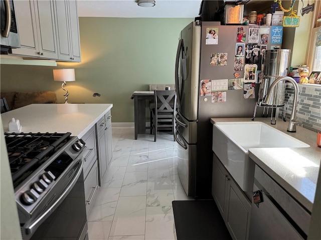 kitchen with stainless steel appliances, gray cabinets, sink, and decorative backsplash