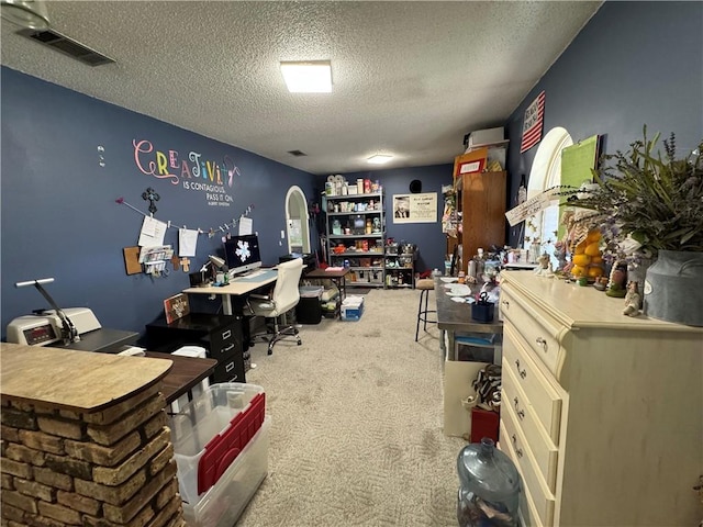 carpeted home office featuring a textured ceiling