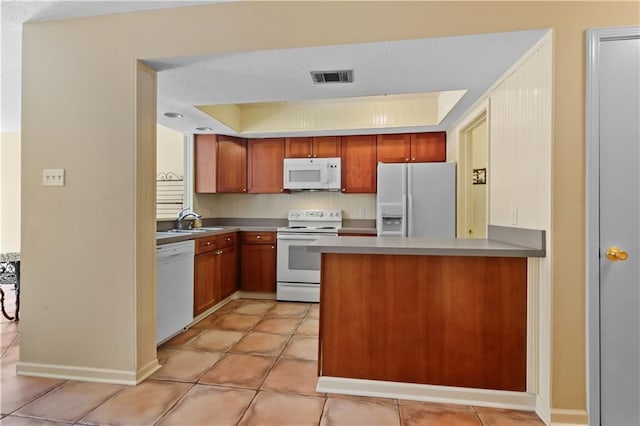 kitchen with a raised ceiling, sink, light tile patterned floors, and white appliances