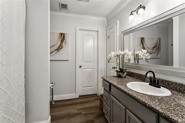 bathroom featuring vanity, ornamental molding, hardwood / wood-style floors, and a textured ceiling