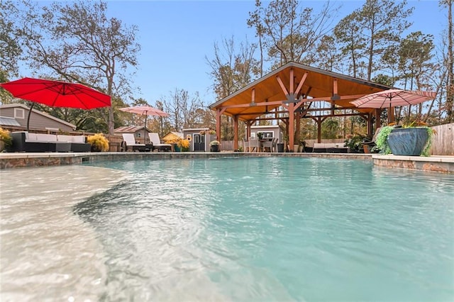 view of pool with a gazebo, an outdoor hangout area, and a shed