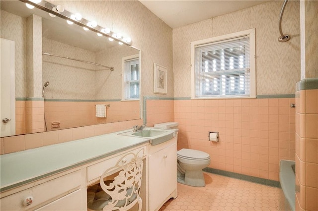 bathroom featuring vanity, toilet, tile walls, and walk in shower