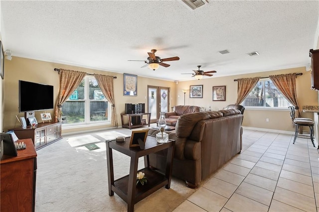 living room featuring ceiling fan, ornamental molding, light carpet, and a textured ceiling