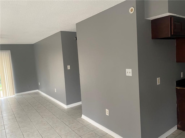 empty room with a textured ceiling and light tile patterned flooring