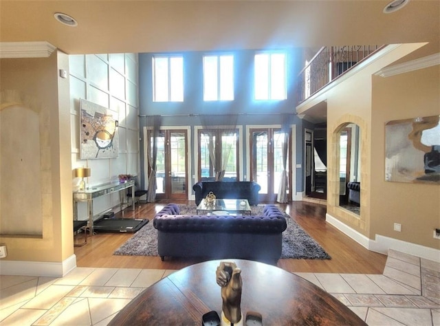 tiled living room with a high ceiling, ornamental molding, and french doors