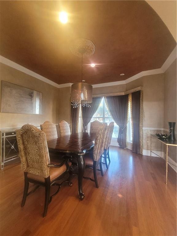 dining area with hardwood / wood-style flooring, crown molding, and an inviting chandelier