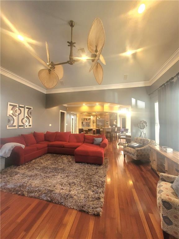 living room with crown molding, vaulted ceiling, hardwood / wood-style floors, and ceiling fan