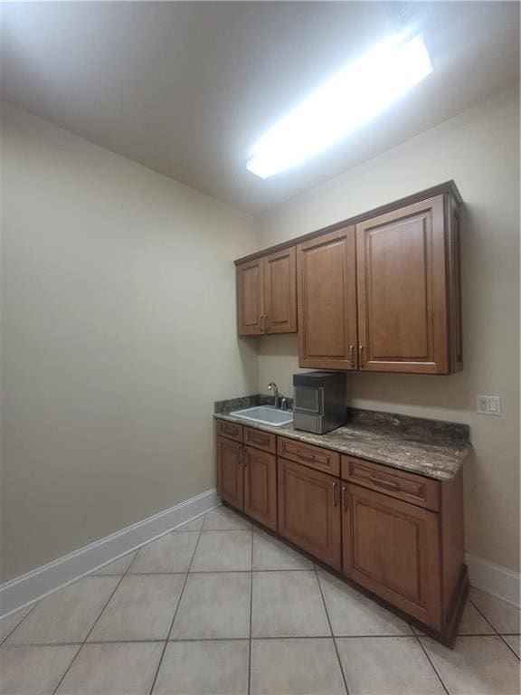 kitchen featuring dark stone countertops, sink, and light tile patterned floors