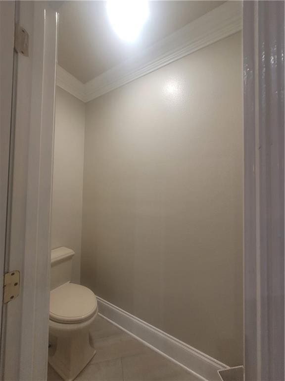 bathroom featuring tile patterned floors, ornamental molding, and toilet