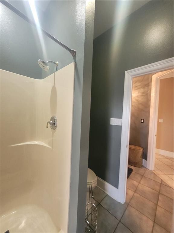 bathroom with a shower, tile patterned floors, and toilet