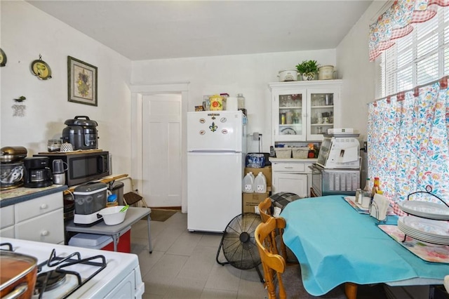 171315 8th St, New Orleans, LA 70115 - kitchen featuring white cabinetry, range with gas stovetop, light countertops, and freestanding refrigerator