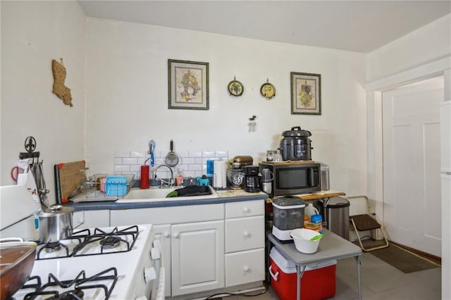 171315 8th St, New Orleans, LA 70115 - kitchen with tasteful backsplash, white cabinets, stainless steel microwave, white gas range, and a sink