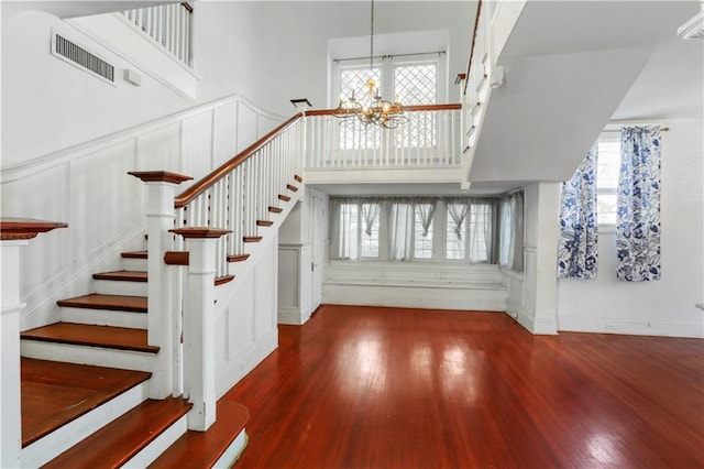 stairs with hardwood / wood-style flooring, plenty of natural light, and a chandelier