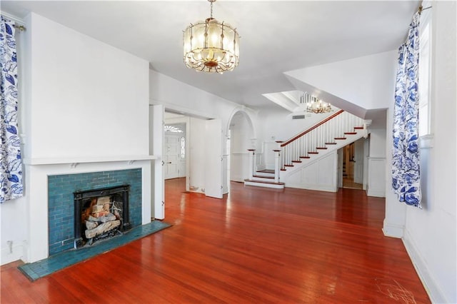 unfurnished living room featuring a tile fireplace, dark hardwood / wood-style floors, and a chandelier