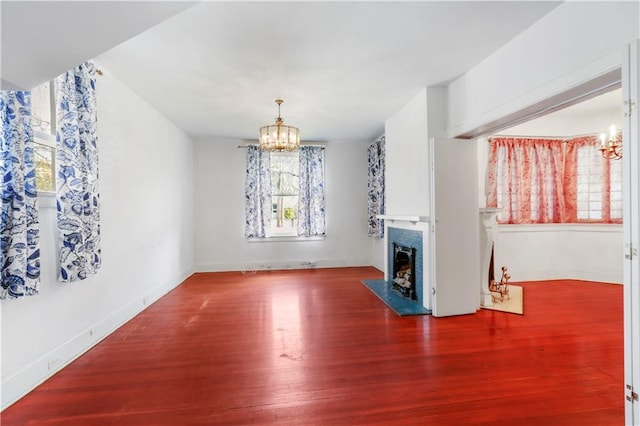 unfurnished living room with an inviting chandelier and hardwood / wood-style flooring