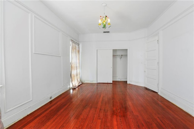 unfurnished bedroom with dark hardwood / wood-style flooring, a closet, and a chandelier