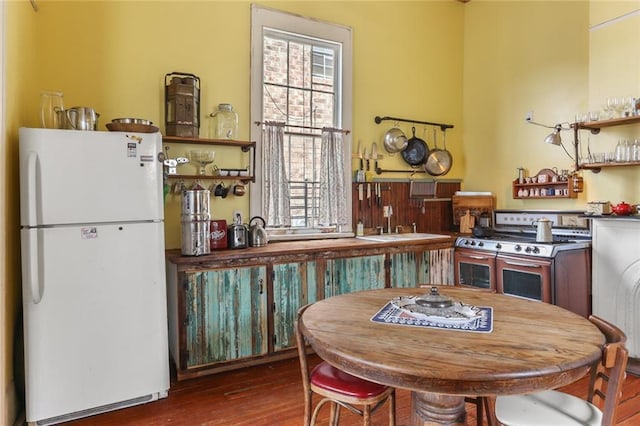 kitchen featuring dark wood-type flooring, range with two ovens, plenty of natural light, and white fridge