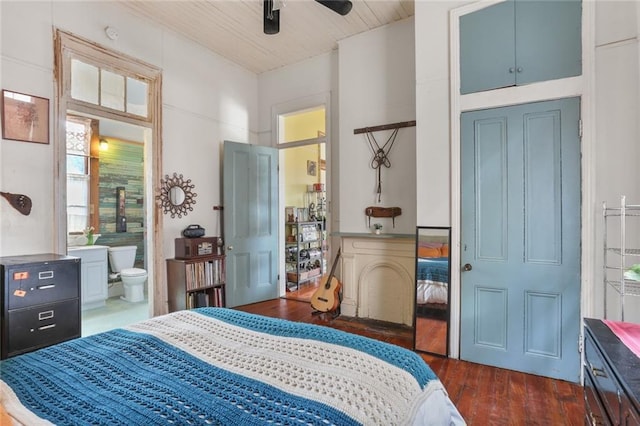 bedroom featuring ensuite bath and dark wood-type flooring