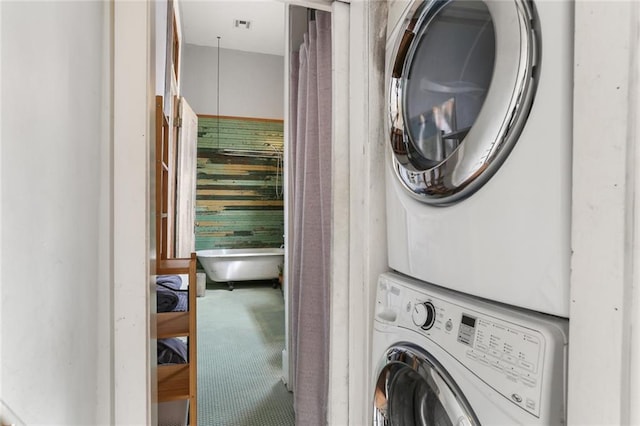 laundry area featuring stacked washer and clothes dryer and carpet