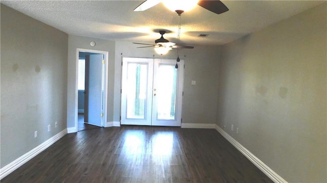 empty room with ceiling fan, dark wood-type flooring, french doors, and a textured ceiling