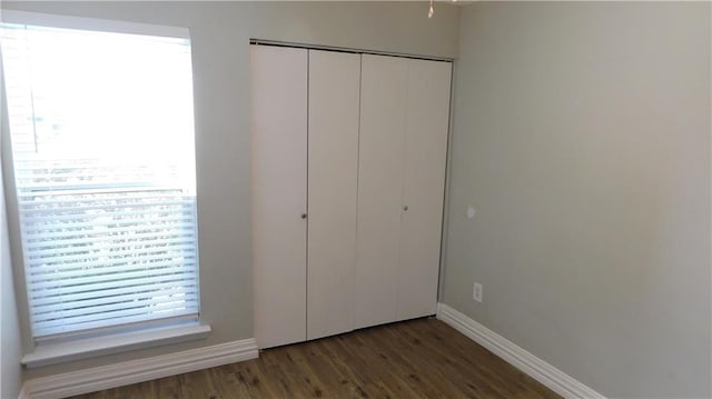 unfurnished bedroom featuring dark hardwood / wood-style floors and a closet