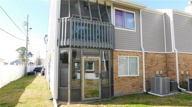 rear view of property featuring a sunroom, a lawn, and central air condition unit