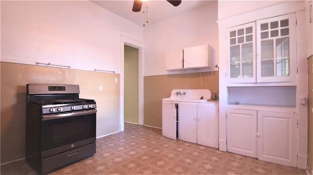 53032 Esplanade Ave, New Orleans, LA 70116 - kitchen featuring gas range, light floors, white cabinets, ceiling fan, and glass insert cabinets