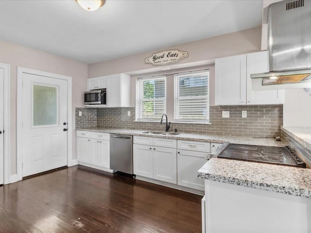 kitchen with stainless steel appliances, white cabinetry, sink, and wall chimney range hood