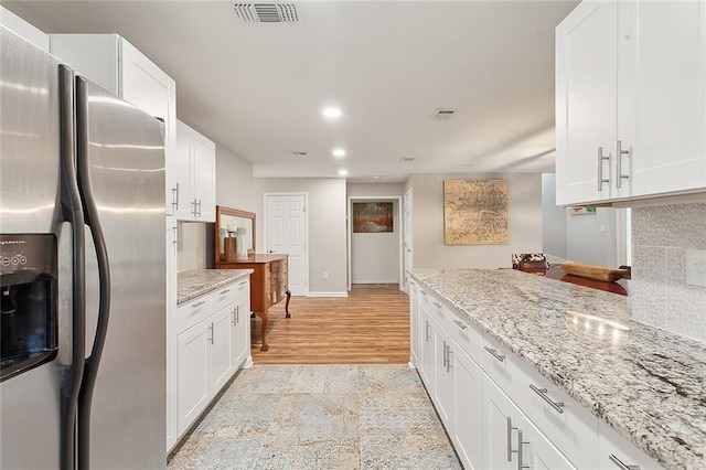 kitchen featuring white cabinetry, light stone counters, and stainless steel fridge with ice dispenser