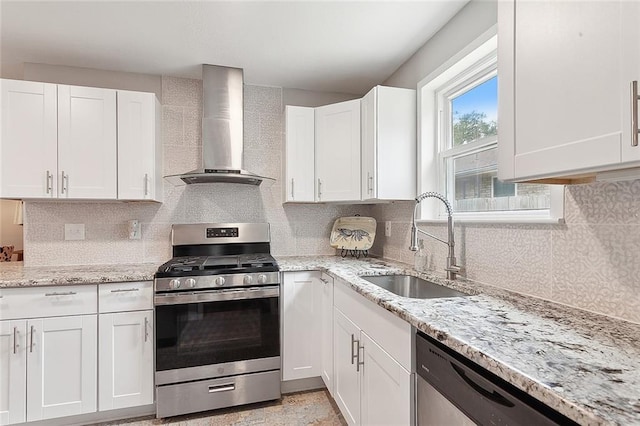 kitchen with appliances with stainless steel finishes, wall chimney exhaust hood, sink, and white cabinets