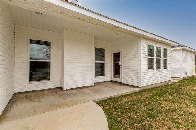 view of exterior entry featuring a yard and a patio