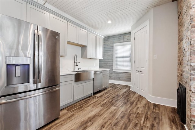 kitchen featuring appliances with stainless steel finishes, sink, hardwood / wood-style floors, and wooden ceiling