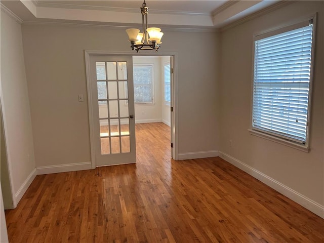 unfurnished dining area with ornamental molding, wood-type flooring, and an inviting chandelier