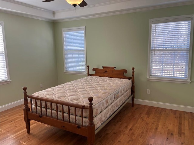 bedroom with multiple windows, hardwood / wood-style floors, and ornamental molding