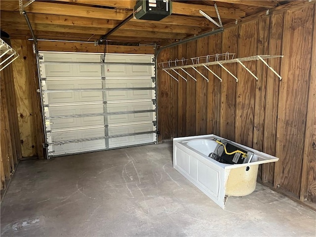 garage with a garage door opener and wood walls