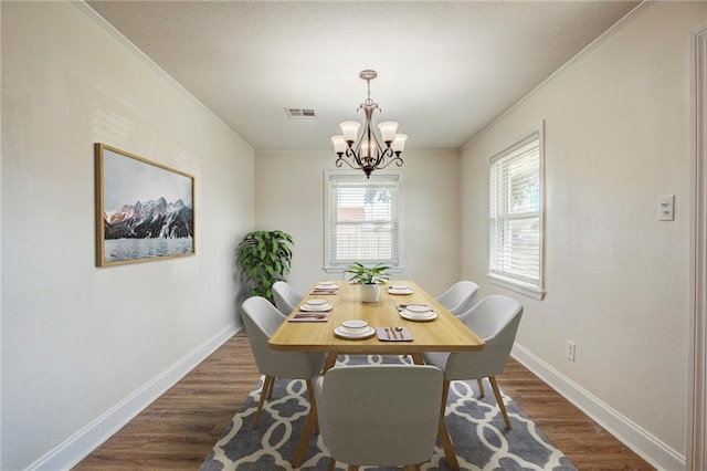 dining room with crown molding, dark hardwood / wood-style flooring, and an inviting chandelier