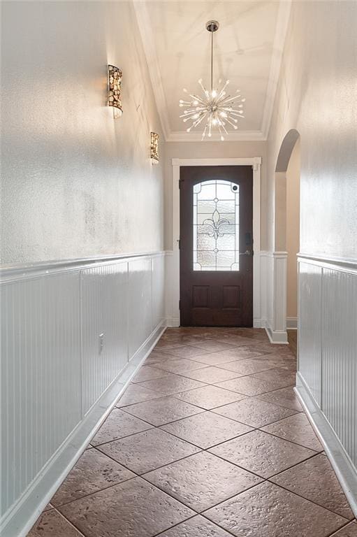 foyer entrance featuring ornamental molding, lofted ceiling, and a chandelier