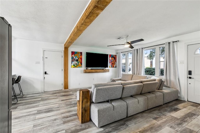 living room featuring beamed ceiling, ceiling fan, and light hardwood / wood-style flooring