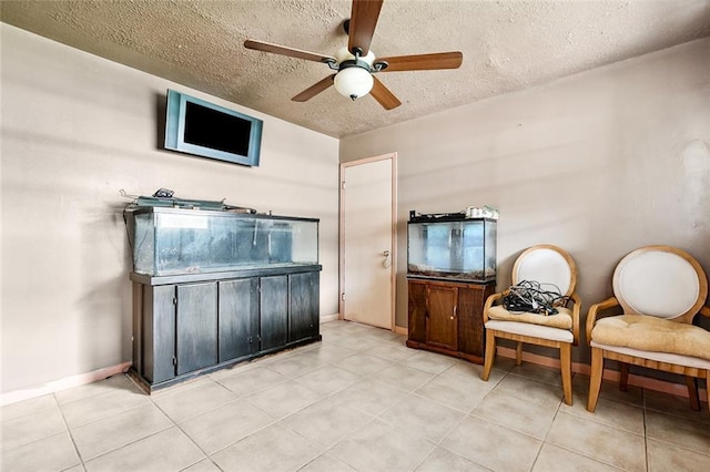 sitting room with ceiling fan, a textured ceiling, and light tile patterned floors