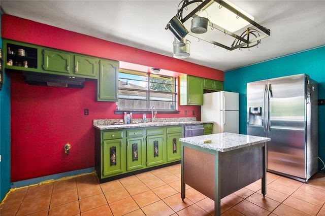 kitchen with green cabinetry, stainless steel appliances, sink, and light tile patterned floors