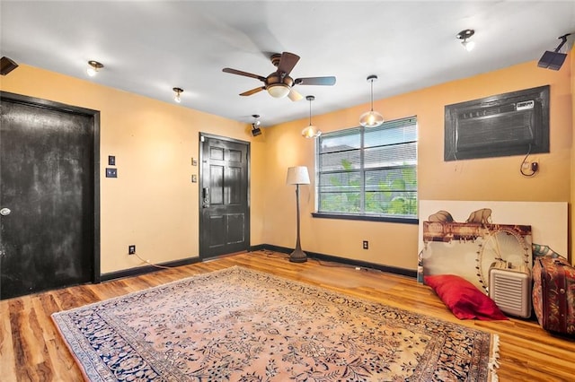 bedroom with ceiling fan, a wall unit AC, and light hardwood / wood-style flooring