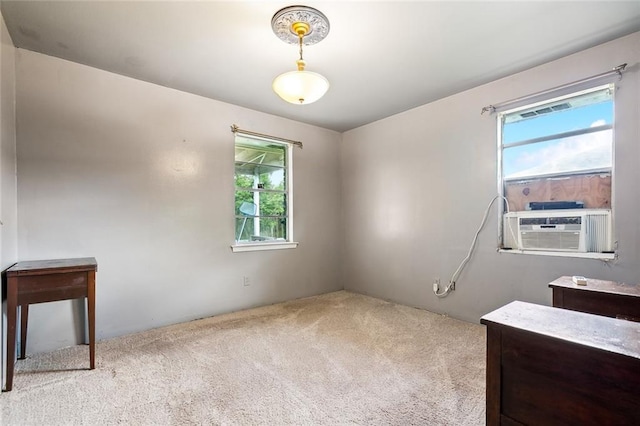 unfurnished room with plenty of natural light, cooling unit, and light colored carpet