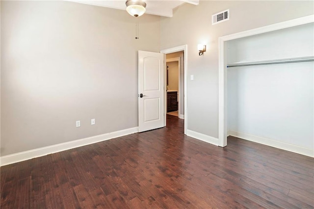 unfurnished bedroom with ceiling fan, dark hardwood / wood-style flooring, and a closet